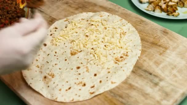 Tortilla de harina llena de queso rallado, carne molida y verduras. Proceso de elaboración de quesadillas mexicanas con carne de res, queso y verduras — Vídeos de Stock