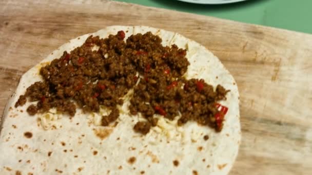 Flour tortilla filled with grated cheese, ground beef and vegetables. Process of making mexican quesadillas with beef meat, cheese and vegetables. Top view — Stock Video