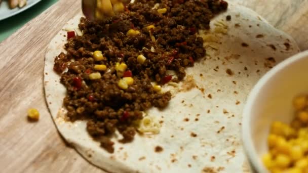 Ajouter le maïs en conserve à la tortilla de farine remplie de fromage râpé, de boeuf haché et de légumes. Procédé de fabrication de quesadillas mexicaines avec viande de bœuf, fromage et légumes — Video