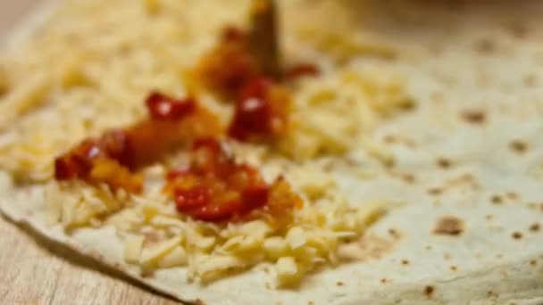 Ajouter les légumes à la tortilla de farine remplie de fromage râpé. Processus de fabrication de quesadillas mexicaines avec viande de poulet, fromage et légumes. Macro — Video