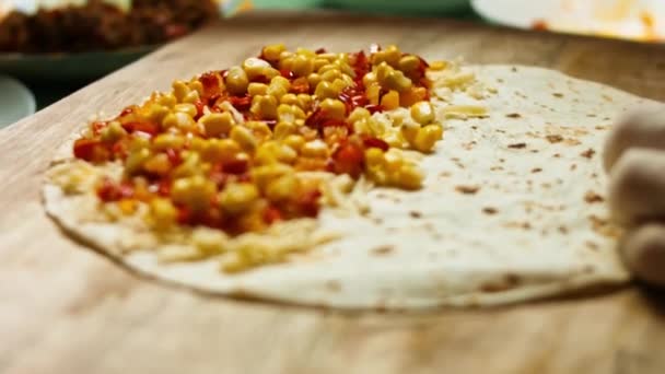 Přidávání smažených kuřecích prsíček k moučné tortille plněné strouhaným sýrem a zeleninou. Proces výroby mexických quesadil s kuřecím masem, sýrem a zeleninou. Makro — Stock video