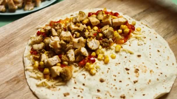 Adding fried chicken breast to flour tortilla filled with grated cheese and vegetables. Process of making mexican quesadillas with chicken meat, cheese and vegetables — Stock Video