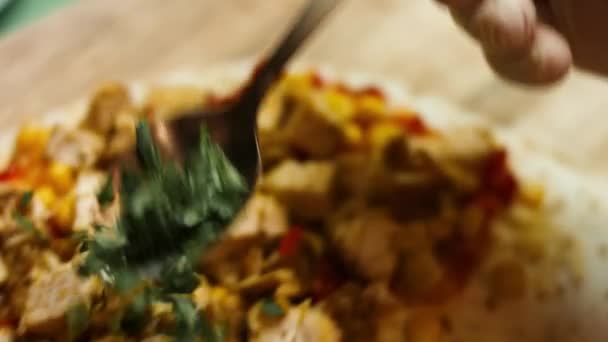 Adding chopped fresh coriander to flour tortilla filled with fried chicken breast, grated cheese and vegetables. Process of making mexican quesadillas. Macro — Stock Video