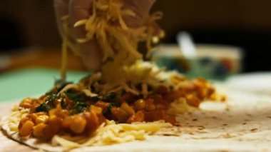 İçinde sebze ve rendelenmiş peynir bulunan un tortilla 'ya ikinci kat peynir ekliyorum. Peynirli ve sebzeli Meksika dürümü yapma süreci. Makro görünüm