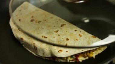 Kızartma tavasında taze sarılmış tavuk quesadilla kızartıyorum. Quesadilla 'yı kaplıyor. Meksika usulü quesadillas yapma süreci