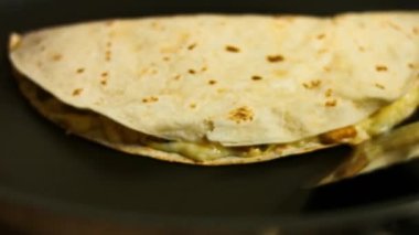 Kızartma tavasında taze sarılmış sebzeli quesadilla kızartıyorum. Dönüp quesadilla 'yı kapatıyorum. Meksika usulü quesadillas yapma süreci. Makro görünüm