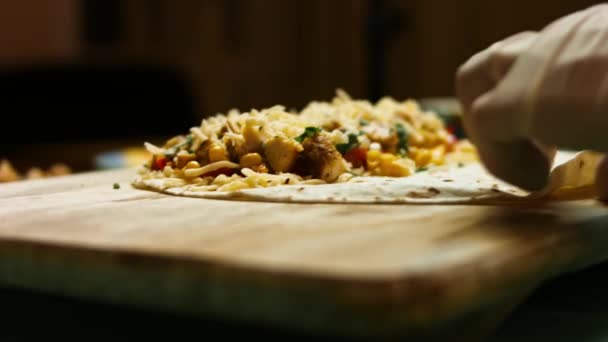 Envolver la tortilla de harina rellena con pechuga de pollo frito, queso rallado y verduras. Proceso de elaboración de quesadillas mexicanas — Vídeos de Stock