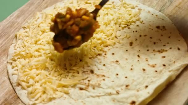 Rendelenmiş peynirle doldurulmuş un tortilla 'ya sebze ekliyorum. Peynirli ve sebzeli Meksika dürümü yapma süreci. Sanatsal çekim — Stok video