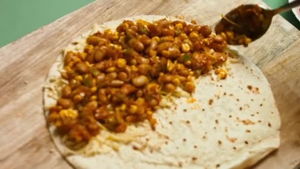 Groenten toevoegen aan bloem tortilla gevuld met geraspte kaas. Proces van het maken van Mexicaanse quesadillas met kaas en groenten — Stockvideo