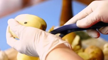 Mutfakta patates soyan bir kadın eli var. Fırında kızartılmış patates pişirme işlemi..