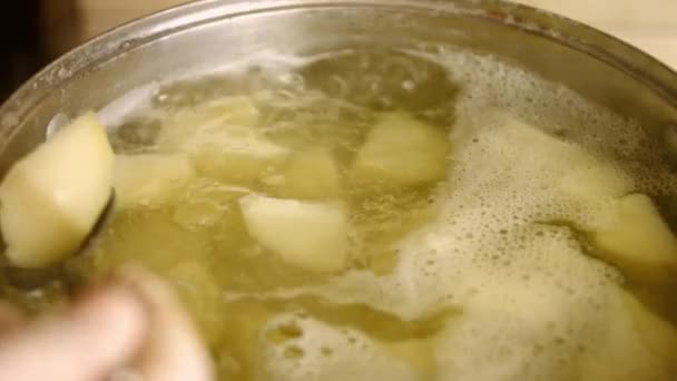 Controllare la morbidezza di una patata bollita con un coltello. Patate dorate bollenti in acqua calda in una pentola. Processo di cottura patate arrosto perfetto forno — Video Stock