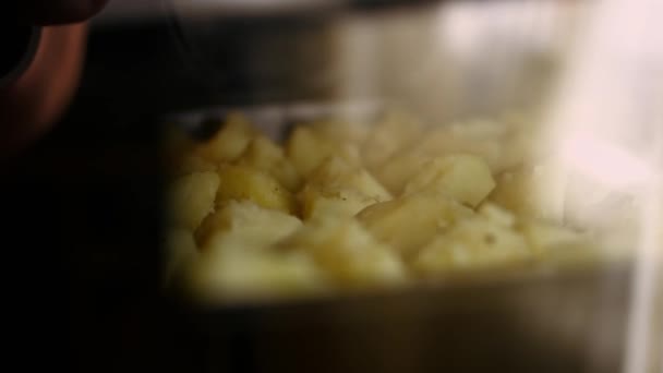 Варена золота картопля, приправлена олією, сіллю і чорним перцем, обсмажується в духовці. Процес приготування ідеальної печі смаженої картоплі — стокове відео