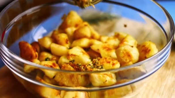 揚げニンニクと細かく刻んだローズマリーをガラスボウルにスパイス黄金のジャガイモを炒めた。完璧なオーブンローストポテトを調理するプロセス — ストック動画