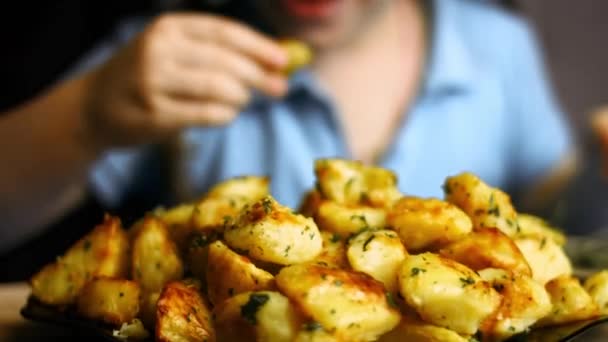 Hermosa rubia 5 años de edad chica comiendo patatas doradas asadas especiadas con ajo frito y romero y perejil fresco en un plato. Proceso de cocción de patatas asadas al horno perfecto — Vídeo de stock