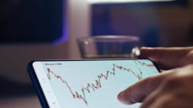 Çay içerken akıllı telefondan şifreli para grafiği analiz ediliyor. Borsada BTC 'den alıntılar. Akıllı telefondaki uygulamayı ekranda görüntüle. Zaman Uygulaması