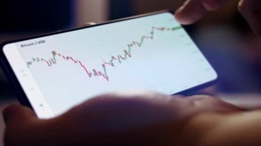 Bir fincan çay içerken akıllı telefondan şifreli para grafiği analiz ediliyor. Borsada BTC 'den alıntılar. Akıllı telefondaki uygulamayı ekranda görüntüle. Makro görünüm