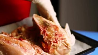 Kadın aşçı eritilmiş tereyağını fırında pişirilmeye hazır büyük, çiğ bir tavuğun üzerine sürüyor. Pişirme işlemi shkmeruli - Gürcü yemeği