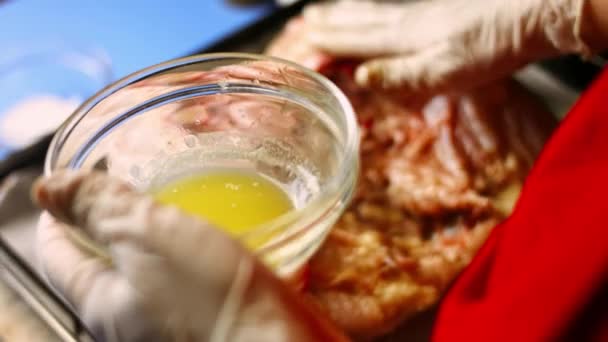 Vrouwelijke chef-kok strooit gesmolten boter over een grote spatchcocked rauwe kip op een bakplaat, klaar om te worden gekookt. Proces van het koken shkmeruli - Georgische gerecht — Stockvideo