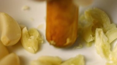 Eldiven giymiş kadın eller kabuktaki soyulmuş karanfilleri sıkıştırıyor. Pişirme işlemi shkmeruli - Gürcü yemeği. Makro görünüm