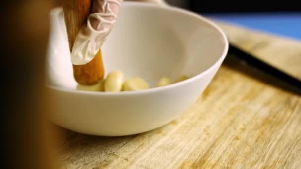 Mãos femininas em luvas pressionando cravos descascados em uma tigela. Processo de cozinhar shkmeruli - prato georgiano. Vista macro — Vídeo de Stock