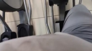 Yürüyen bir simülatör üzerinde alıştırmalar. Bacakların üst görüntüsü. Adam kulübe spor için gidiyor. Akıllı telefondan çekim