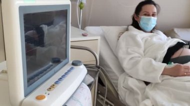 Kemerlerin karnındaki hamile kadın fetüs testini izliyorum. Hastanede Sağlık Teşhisi