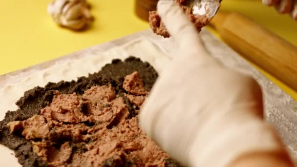Руки кладут миску с избитым яйцом близко к сформированной сырой говядине Веллингтон. 4k видео — стоковое видео