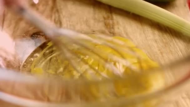 Macro view of mixing fresh eggs, flour and milk with steel hand mixer in a glass bowl. Process of preparing pancakes. 4K cinematography video — Stock Video