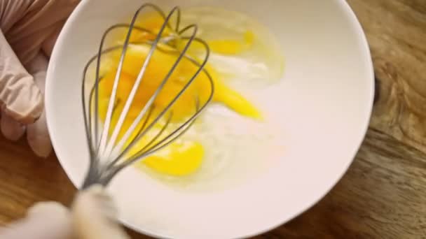 Sluiten kloppen eieren met de keuken garde in metalen kom voor 's morgens omelet of roerei. Kook eieren voor het maken van deeg in de bakkerij. Ontbijtconcept koken — Stockvideo