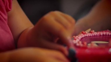 Mutlu küçük kız doğum gününü pastasındaki mumları söndürerek kutluyor. Ebeveynler ve büyükbabalar küçük çocuğun pasta mumlarını söndürmesini izliyorlar.