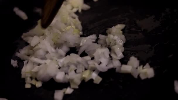 Die gebratenen Zwiebelscheiben in einer heißen Pfanne mit einem hölzernen Drechsel umrühren. Nahaufnahme — Stockvideo