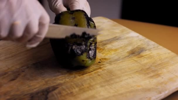 Сожгите ножом сожжённую пленку из зелёного перца. Я готовлю мексиканский фаршированный Poblano Peppers в ореховом соусе. 4k видео — стоковое видео