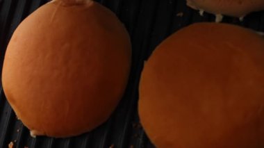 Hamburger ekmeğini ızgarada kızart. Klasik Amerikan hamburgerinin tadına bak. 4k video