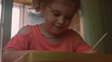 Kız kağıda resim çiziyor ve zevk alıyor. Masa eğitimi. 4k video