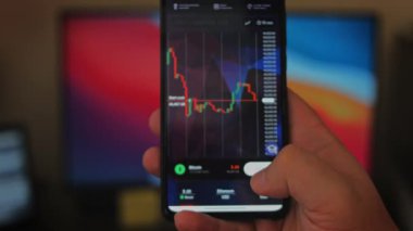Bitcoin Kripto para birimi Altın Bitcoin BTC Bit Bozukluğu üzerindeki telefon siyah arka planda Bitcoin paralarını kapatın. Telefon ekranı borsaları dinamik şemayı yükseltiyor. 4k makro video