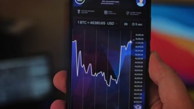 Bitcoin Kripto para birimi Altın Bitcoin BTC Bit Bozukluğu üzerindeki telefon siyah arka planda Bitcoin paralarını kapatın. Telefon ekranı borsaları dinamik şemayı yükseltiyor. 4k makro video