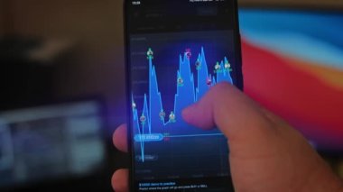 Bitcoin Kripto para birimi Altın Bitcoin BTC Bit Bozukluğu üzerindeki telefon siyah arka planda Bitcoin paralarını kapatın. Telefon ekranı borsaları dinamik şemayı yükseltiyor. 4k makro video
