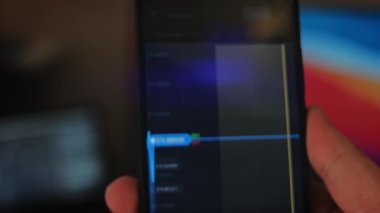 Bitcoin Kripto para birimi Altın Bitcoin BTC Bit Bozukluğu üzerindeki telefon siyah arka planda Bitcoin paralarını kapatın. Telefon ekranı borsaları dinamik şemayı yükseltiyor. 4k makro video