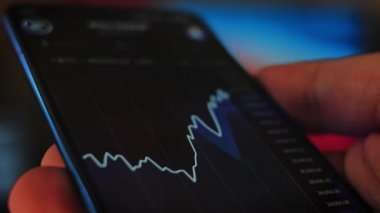 Bitcoin Kripto para birimi Altın Bitcoin BTC Bit Bozukluğu üzerindeki telefon siyah arka planda Bitcoin paralarını kapatın. Telefon ekranı borsaları dinamik şemayı yükseltiyor. 4k makro video