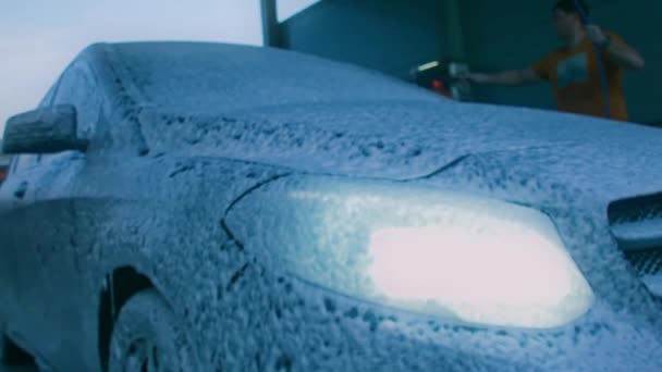De man wast de auto met schuim. Nachtfilmen — Stockvideo