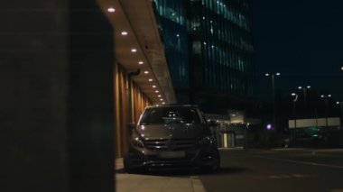 Araba, modern şehrin arka planında geceleyin çekildi. Çok katlı evler. 4k video