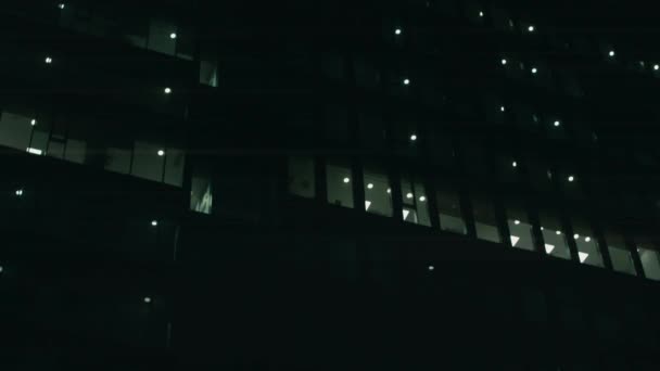 Wielopiętrowy dom kręcony nocą. Widać biura z włączonymi światłami. 4k wideo — Wideo stockowe