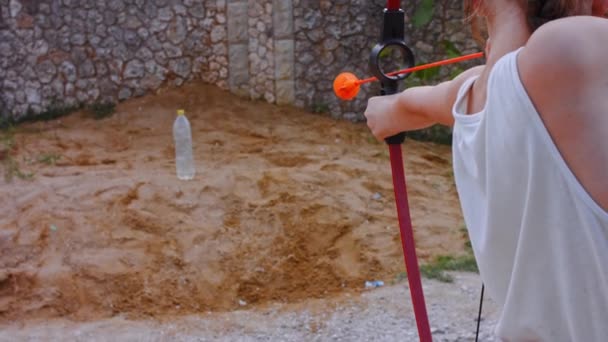 Barn bågskytt med långt hår skjuter från en båge med pilar på ett mål, vy bakifrån. 4k-video — Stockvideo