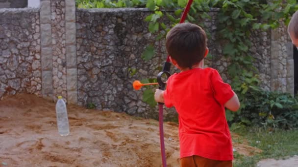 Kinderbogenschütze mit langen Haaren schießt aus einem Bogen mit Pfeilen auf ein Ziel, Blick von hinten. 4k-Video — Stockvideo