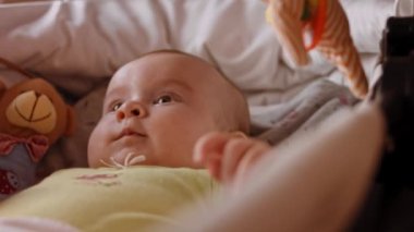 Çocuk Beşiğinde Arkaya Yatan Sevimli Yeni Doğan Bebeğin Güzel Yakın Çekimi. Heyecanlı bir yenidoğan çocuğun Dönen Oyuncaklara Bakışlı Portresi. Çocukluk kavramı, Yeni Yaşam, Ebeveynlik