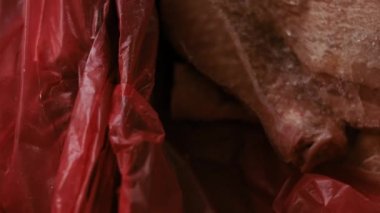 Eldivenli ellerin yakın plan görüntüsü tavuk bacağını bir kutudan ayrı plastik poşetlere paketliyor. Evde daha fazla kullanılmak üzere dondurulmuş etin süreci. Işık oynatma ile 4k video