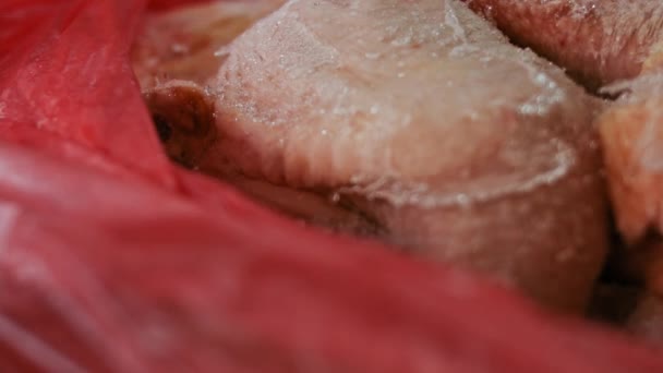 Close-up zicht van de handen in handschoenen verpakken kippenpoten uit een doos in individuele plastic zakken. Invriezen van vlees voor verder gebruik thuis. 4k video met lichtspel — Stockvideo