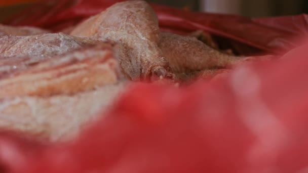 Närbild av händer i handskar som packar kycklingben från en låda till enskilda plastpåsar. Bearbetning av fryst kött för vidare användning i hemmet. 4k video med lätt uppspelning — Stockvideo