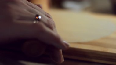 Kadın elleri hamuru ahşap tahtaya, makro manzaraya serer.