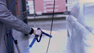 Vitiligo giysili genç adam arabasını oto yıkamada köpükle temizliyor..